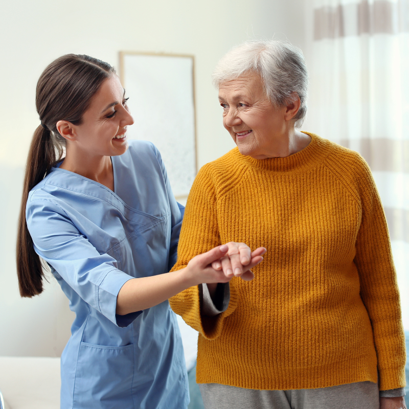 An image of a carer in blue scrubs supporting an elderly individual with home tasks.